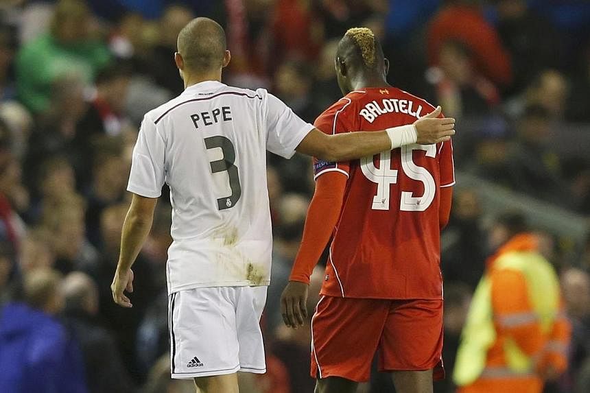 Liverpool's Mario Balotelli (right) walks off the pitch at half-time with Real Madrid's Pepe, before swapping shirts in the tunnel, during their Champions League Group B soccer match at Anfield in Liverpool, northern England on Oct 22, 2014. -- PHOTO
