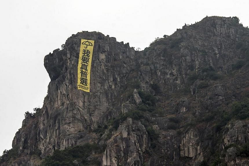 A large banner hung by pro-democracy protesters is seen at Lion Rock, overlooking Kowloon in Hong Kong, on Oct 23, 2014. The yellow banner featured the slogan "I want genuine universal suffrage" and an umbrella, the symbol adopted by democracy protes