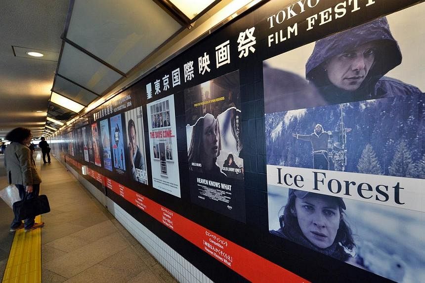 A pedestrian looking at posters of movies which will be screening at the Tokyo International Film Festival in Tokyo on Oct 22, 2014.&nbsp;The Tokyo International Film Festival opens on Thursday with its focus heavily on Japanese animated movies and w