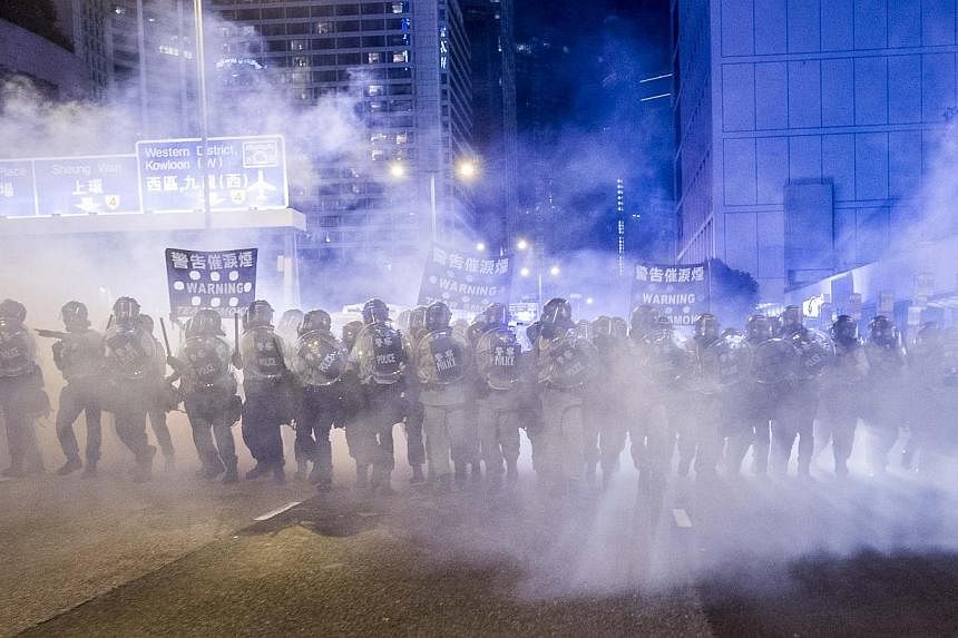 Police officers stand in a cloud of tear gas during a demonstration in Hong Kong on Sept 28, 2014. Britain said on Oct 22 it was likely to consider whether it needed to block British firms exporting tear gas to Hong Kong after police there used it ag