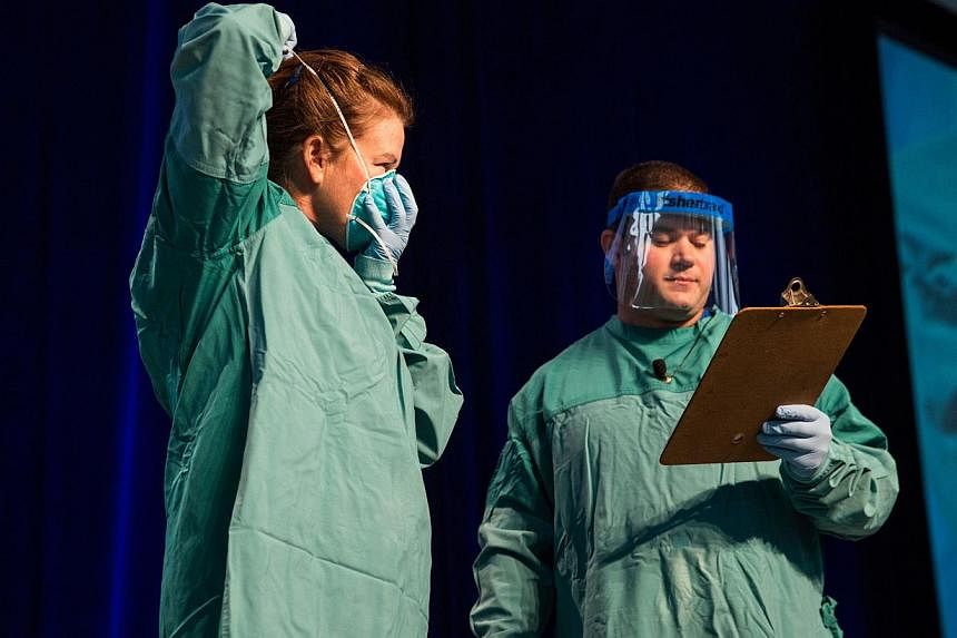 Barbara Smith (left), a nurse with Mount Sinai Health System, and Bryan Christensen, a doctor and member of the Center for Disease Control's Domestic Infection Control Team for the Ebola Response, demonstrate to health care professionals how to prope