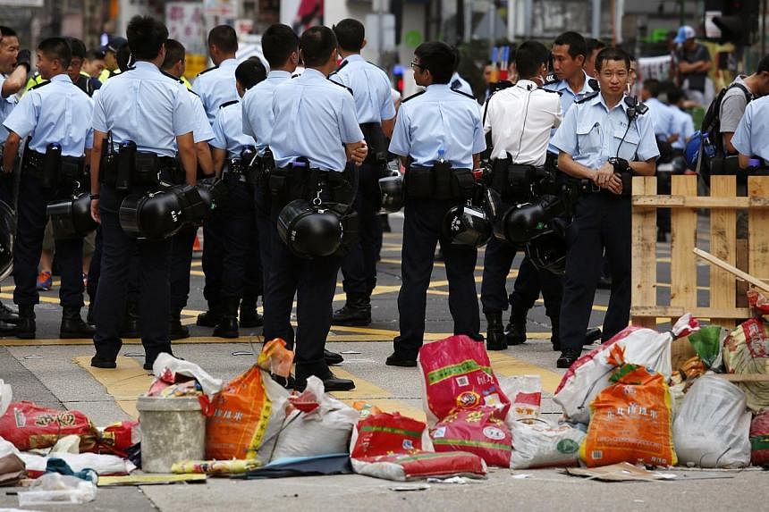 Police officers patrol in front of a barricade set up by pro-democracy protesters, and was partly demolished by anti-Occupy protesters, at Mongkok shopping district in Hong Kong, on Oct 22, 2014. -- PHOTO: REUTERS