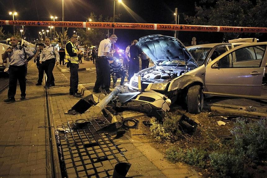 Israeli policemen inspect a car wreck in Jerusalem on Oct 22, 2014. A baby was killed and eight people injured when a car slammed into pedestrians at a Jerusalem light railway stop on Wednesday, emergency services said, in what police described as a 