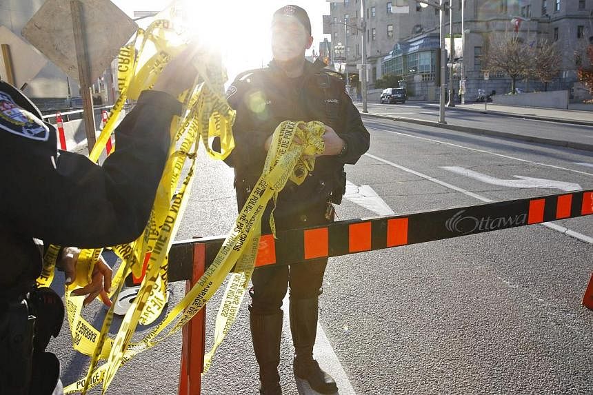 Police officers gather police tape following shootings in downtown Ottawa on Oct 22, 2014. -- PHOTO: REUTERS
