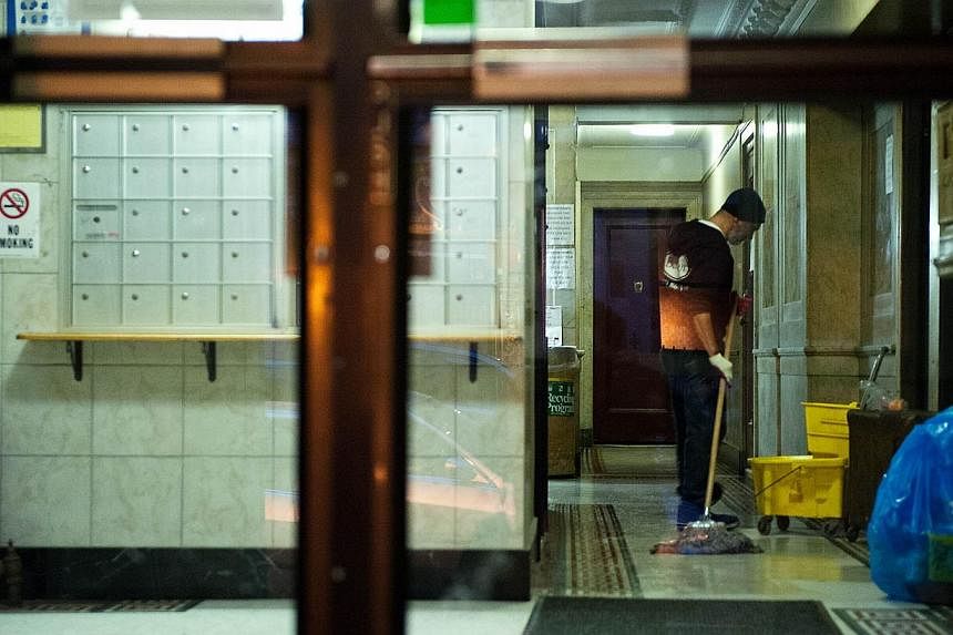 A man mops the lobby of the apartment building of Dr Craig Spencer in New York City on Oct 23, 2014. The Doctors Without Borders physician has tested positive for Ebola. -- PHOTO: AFP