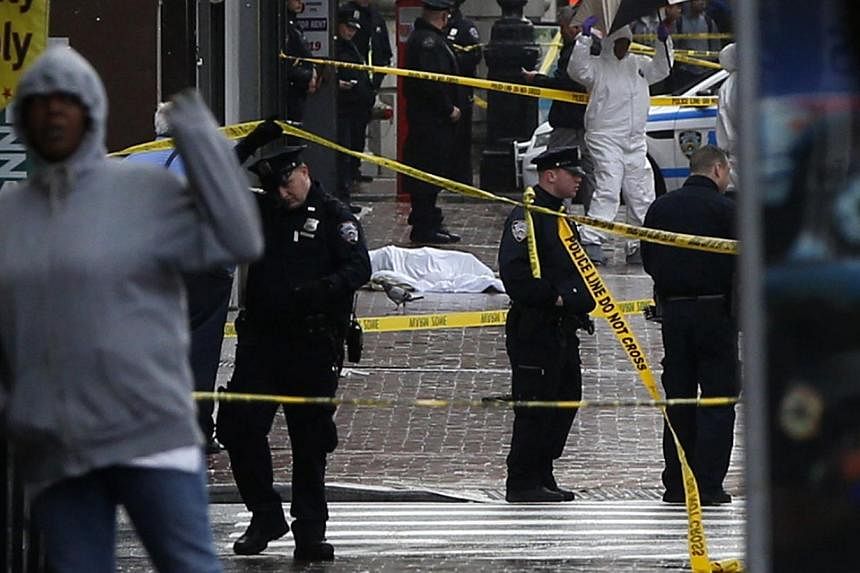 A body lays covered on Jamaica Avenue near 162nd street in the borough of Queens in New York on Oct 23, 2014. -- PHOTO: REUTERS