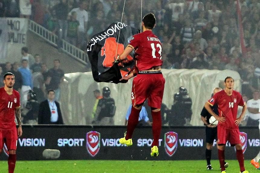 Serbia's defender Stefan Mitrovic grabs a flag with Albanian national symbols flown by a remotely operated drone during the UEFA Euro 2016 group I qualifying football match between Serbia and Albania in Belgrade on Oct 14, 2014.&nbsp;Albania's footba