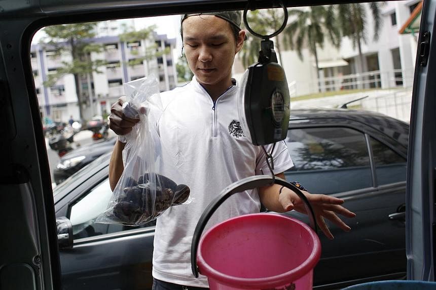 Ah Hua Kelong's Mr Wong Jing Kai weighing a batch of green mussels during his delivery run. The seafood is delivered within 12 hours of its harvest. Mr Terence Tee, 38, receiving his order from Ah Hua Kelong's business development manager, Mr Wong Ji