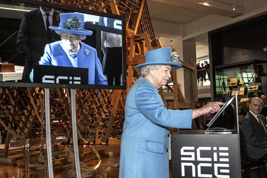Britain's Queen Elizabeth presses a button to send her first Tweet during a visit to the 'Information Age' Exhibition at the Science Museum, in London on Oct 24, 2014. &nbsp;-- PHOTO: AFP