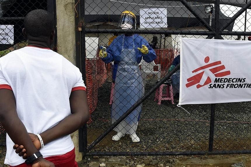 A picture taken on Sept 26, 2014 shows a man asking a health worker about his wife being treated at the medical centre of Doctor Without Borders (MSF) treating people infected with the Ebola virus in Monrovia. -- PHOTO: AFP