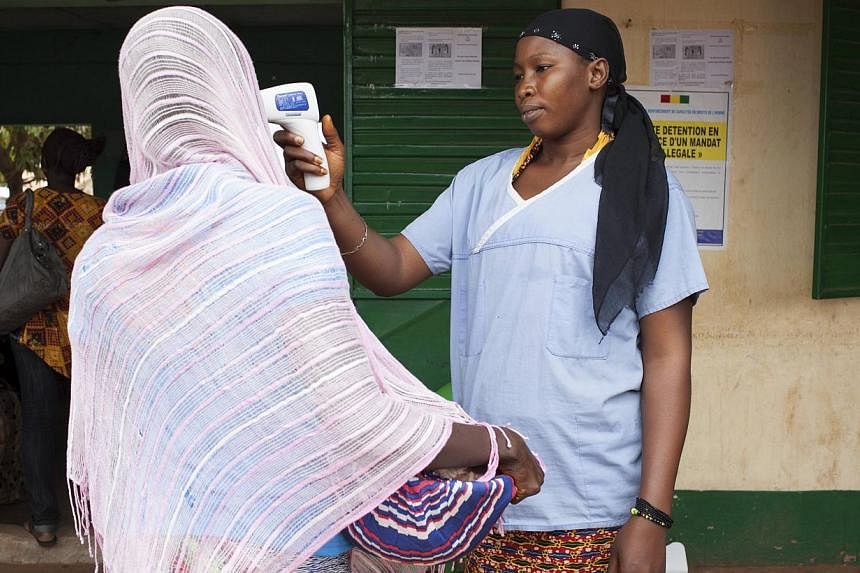 A health worker checks the temperature of a woman leaving Guinea at the border with Mali in Kouremale on Oct 2, 2014. A two-year-old girl who was Mali's first confirmed case of Ebola has died, a local health official said on Friday.&nbsp;-- PHOTO: RE