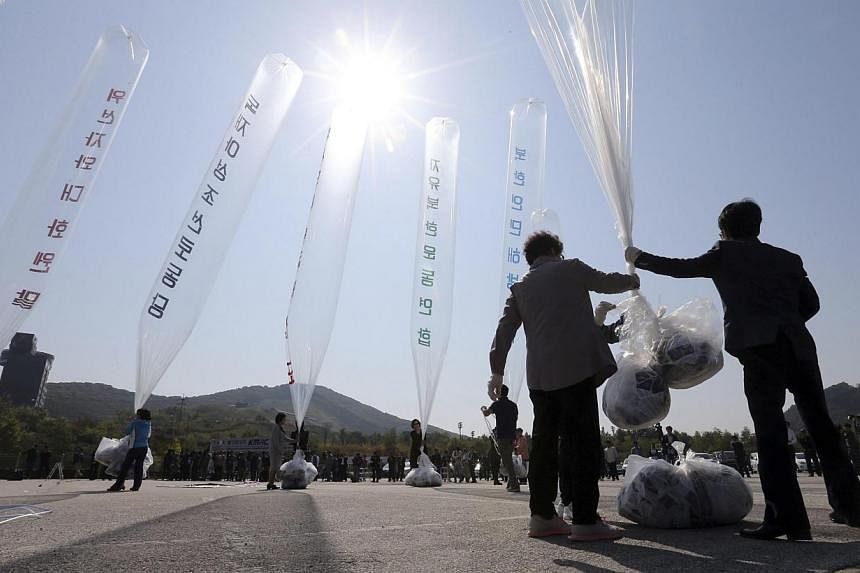 Former North Korean defectors hold a balloon containing anti-North Korea leaflets as they prepare to release them toward the North, near the demilitarized zone in Paju on Oct 10, 2014. -- PHOTO: REUTERS