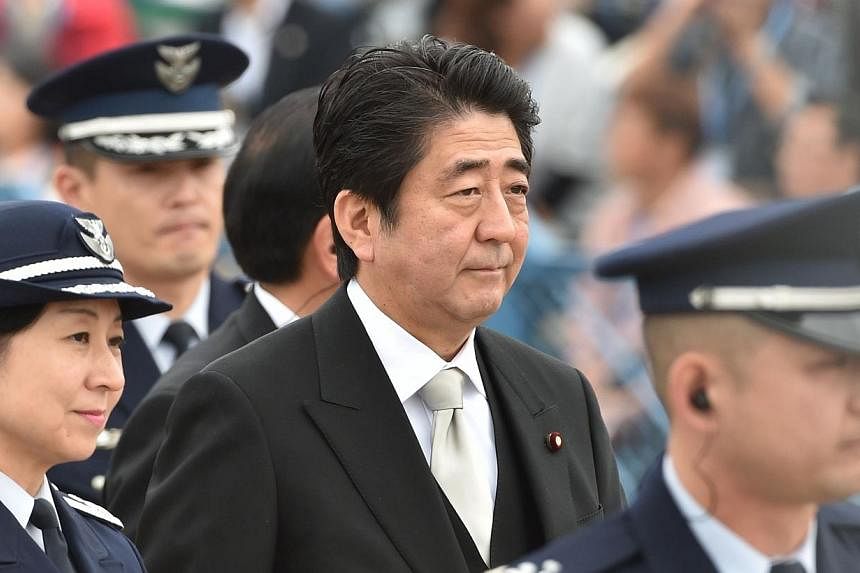 Japanese Prime Minister Shinzo Abe (centre) arrives at a review ceremony at the Japan Air Self-Defense Force's Hyakuri air base at Omitama in Ibaraki prefecture on Oct 26, 2014. -- PHOTO: AFP
