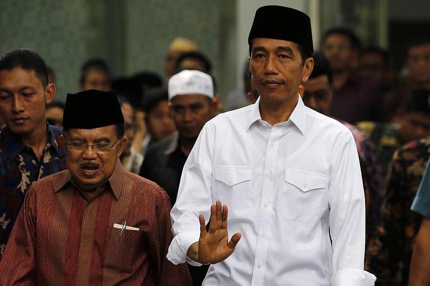 Indonesia's President Joko Widodo (right) waves as he walks with vice president Yusuf Kalla after Friday prayers at the Presidential palace in Jakarta, on Oct 24, 2014. -- PHOTO: REUTERS