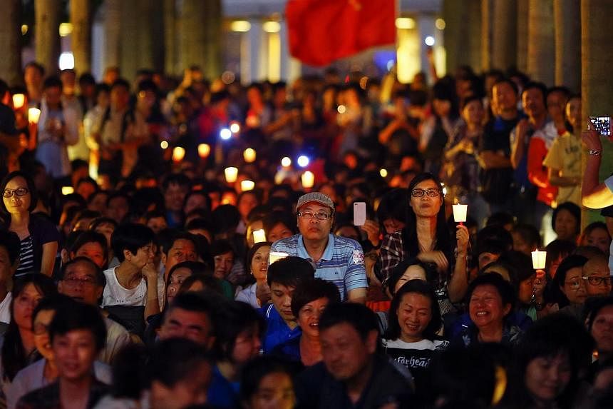 Anti-Occupy protesters hold candles and a Chinese flag as they gather to oppose actions of pro-democracy groups in Hong Kong on Oct 25, 2014. -- PHOTO: REUTERS