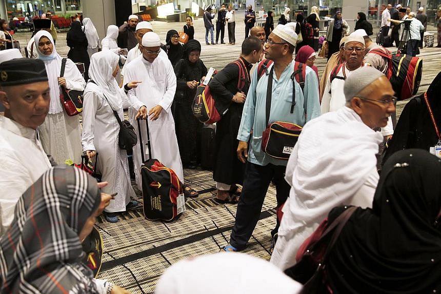 About 120 pilgrims returning from their haj journeys in Saudi Arabia were greeted by Minister-in-charge of Muslim Affairs Yaacob Ibrahim after they touched down at Changi Airport on Sunday morning. -- ST PHOTO:&nbsp;LAU FOOK KONG
