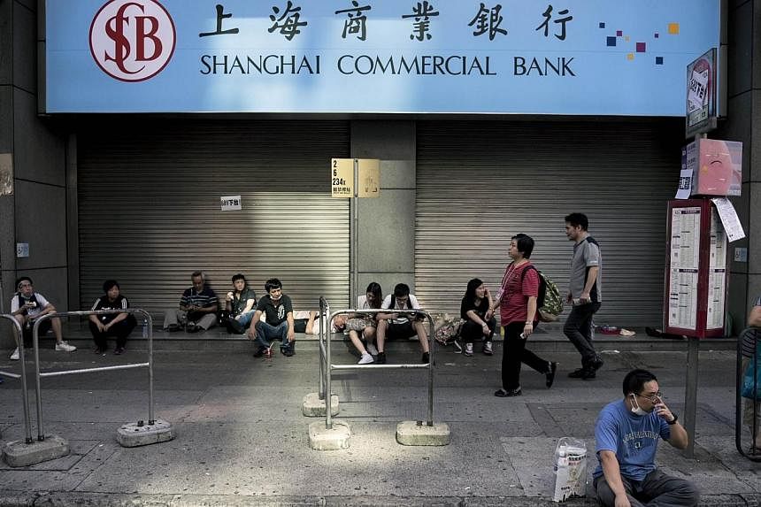 People gather next to a shuttered branch of the Shanghai Commercial Bank as a pro-democracy protest continues on Nathan Road, a major route through the heart of the Kowloon district of Hong Kong, on Sept 29, 2014. -- PHOTO: AFP
