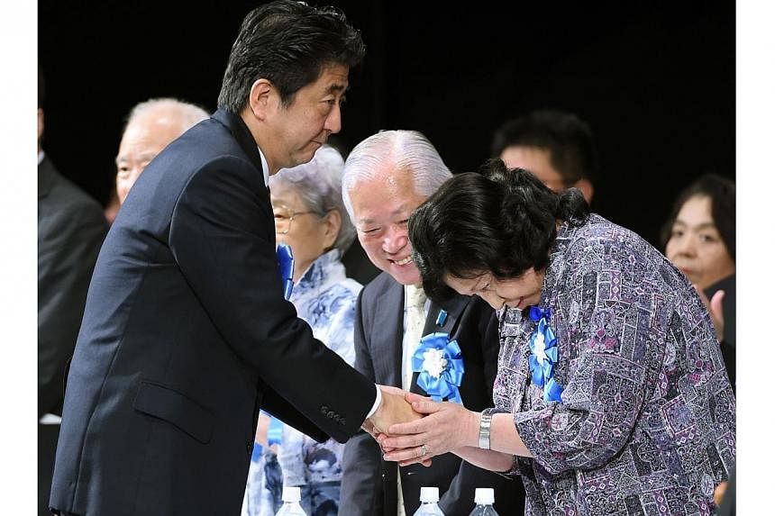 Japanese Prime Minister Shinzo Abe (left) shakes hands with abduction victim Hitomi Soga (right) while entering a rally to support families of abduction victims by North Korea in Tokyo on Sept 13, 2014.&nbsp;A Japanese delegation is to arrive in Nort