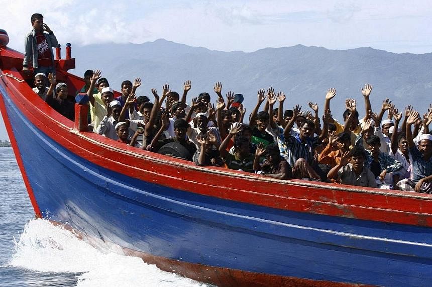 Ethnic Rohingya refugees from Myanmar wave as they are transported by a wooden boat to a temporary shelter in Krueng Raya in Aceh Besar in this April 8, 2013 file photo.&nbsp;A climate of fear in Myanmar's Rakhine state is pushing stateless Rohingya 