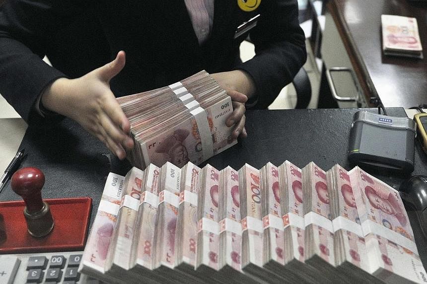 A clerk arranges bundles of 100 Chinese yuan banknotes at a branch of China Merchants Bank in Hefei, Anhui province in this March 17, 2014 file photo. -- PHOTO: REUTERS