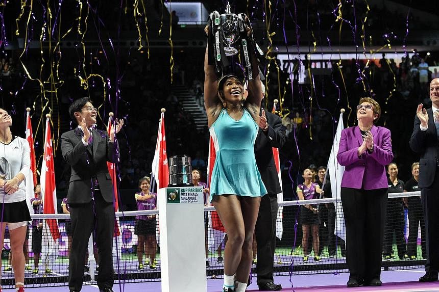 Serena Williams of the US (middle) lifts the trophy at the podium after defeating Simona Halep of Romania in the finals of the Women's Tennis Association (WTA) finals in Singapore on Oct 26, 2014. -- PHOTO: AFP