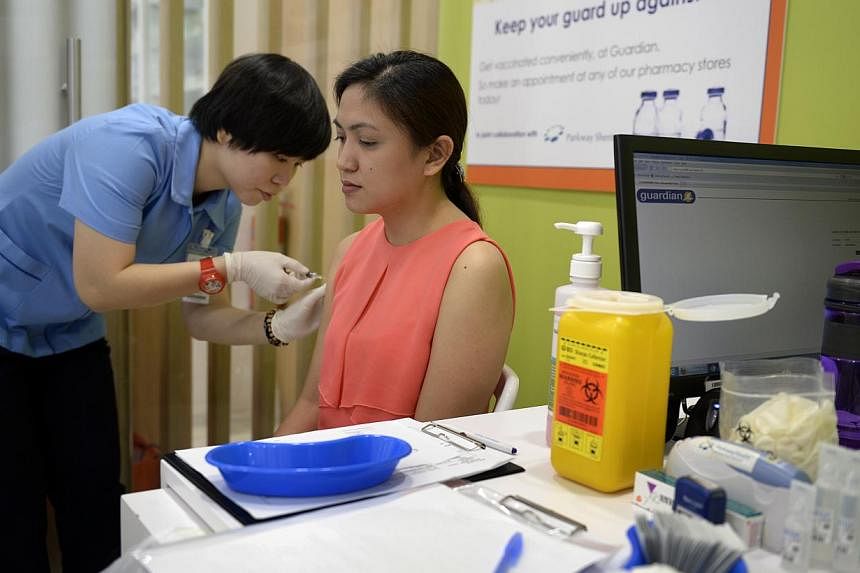 Krisiel Francisco (seated), 28, a pharmacy technician receiving a flu vaccination from Carol Ong, senior staff nurse from Parkway Shenton at the Guardian Plus outlet at Ngee Ann City. -- ST PHOTO: DESMOND LIM