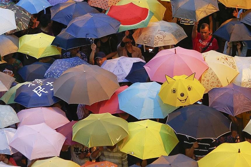 Protesters open their umbrellas, symbols of pro-democracy movement, as they mark exactly one month since they took the streets in Hong Kong's financial central district on Oct 28, 2014.&nbsp;-- PHOTO: REUTERS