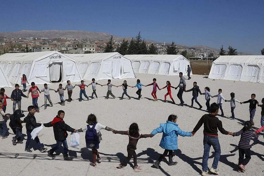 Syrian refugee children join hands as they play at a makeshift school, supported by UNICEF and in cooperation with the Beyond Association, in Zahle in the Bekaa valley on Oct 22, 2014.&nbsp;At least 2.6 million children have fallen below the poverty 