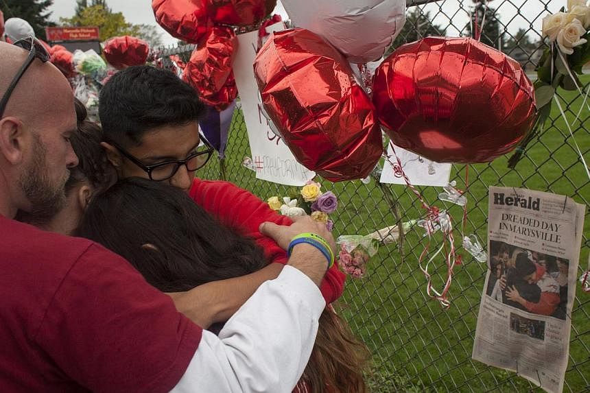 Members of the community and students grieve beside a makeshift memorial at Marysville-Pilchuck High School in Marysville, Washington&nbsp;on Oct 26, 2014. -- PHOTO: AFP