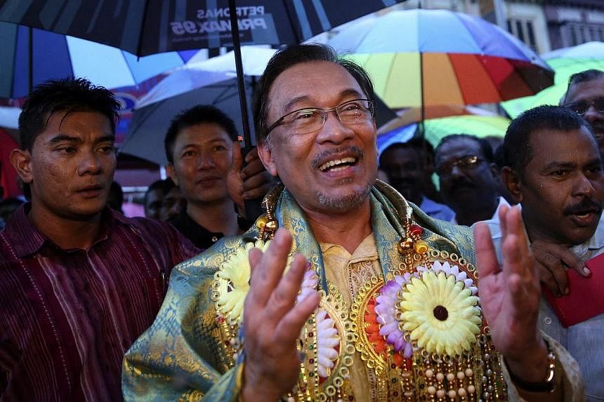 Malaysia's opposition leader Anwar Ibrahim sings on a street in Klang, near Kuala Lumpur, as part of a campaign to seek support ahead of his final appeal against a conviction for sodomy next week, on Oct 21, 2014. -- PHOTO: REUTERS