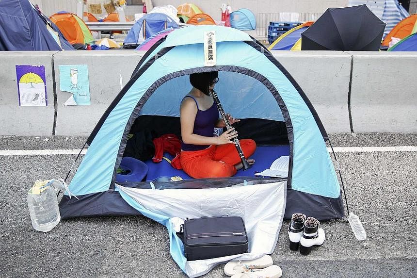 An activist practices oboe in her tent set-up in a part of Hong Kong's financial central district occupied by pro-democracy protesters. -- PHOTO: REUTERS