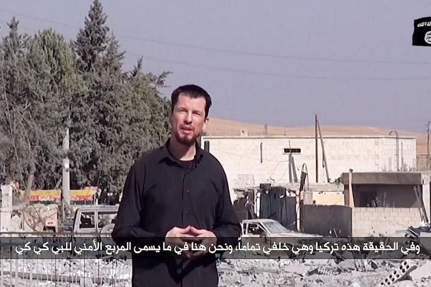 An image grab taken from a video released by the Islamic State (IS) group group via Youtube on Oct 27, 2014 purportedly shows 43-year-old kidnapped British reporter John Cantlie standing in a war-damaged town, talking to the camera and rejecting US c