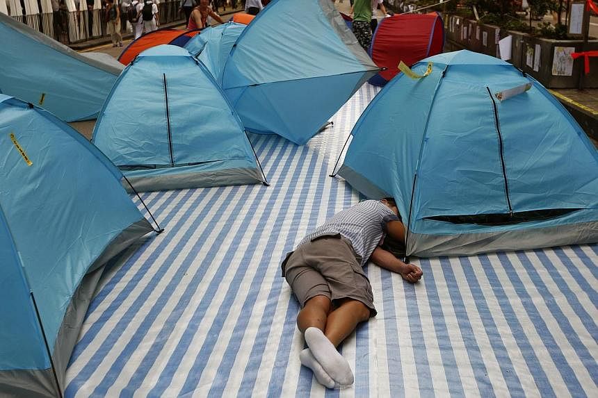 A pro-democracy protester sleeps as tents are blown away by a gust of wind in the Mong Kok shopping district of Hong Kong, Oct 27, 2014. -- PHOTO: REUTERS