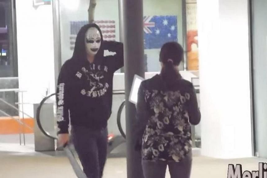 A screengrab from the Purge Prank video posted on YouTube by MerlionTV, which shows a masked man wielding a knife scaring a woman. -- PHOTO: SCREENGRAB FROM YOUTUBE