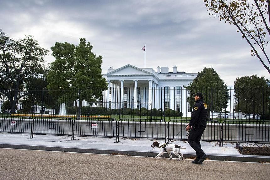 A US Secret Service Uniformed Division officer and his K-9 dog patrol the fence line of the White House in Washington, DC, on Oct 23, 2014. -- PHOTO: AFP