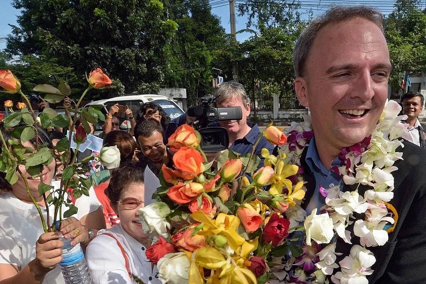 British activist Andy Hall (right) receives flowers from his supporters as he arrives at a court in Bangkok on Oct 29, 2014.&nbsp;A Thai court dismissed a defamation charge against a British activist on Wednesday in a case linked to a report he co-au