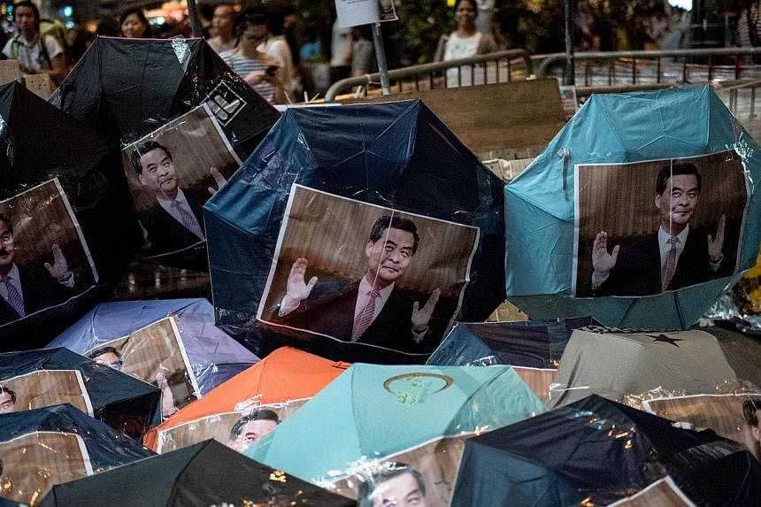 Images of Hong Kong Chief Executive Leung Chun-ying are pasted onto umbrellas -- symbols of the Hong Kong pro-democracy protests -- at a barricade set up in the Mongkok district of Hong Kong on Oct 18, 2014.&nbsp;History&nbsp;rarely moves in ways sim