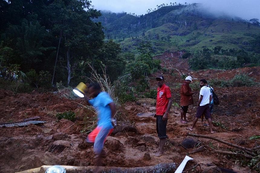 Sri Lankan residents walk through the site of a landslide caused by heavy monsoon rains in Koslanda village in central Sri Lanka on Oct 29, 2014.&nbsp;More than 100 people are believed to have been killed on Wednesday in a landslide in hilly south-ce