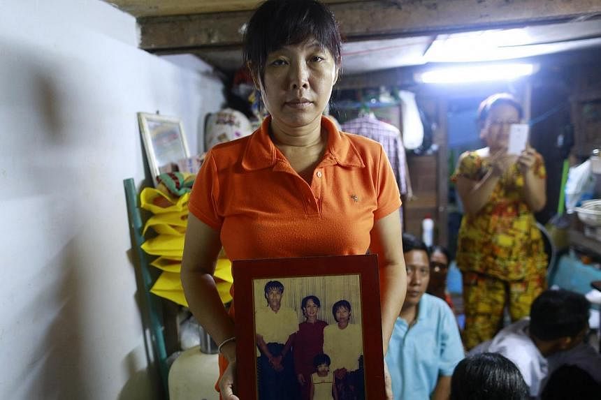 Than Dar, the wife of slain journalist Par Gyi, holds a family photograph showing herself, her husband and daughter posing with Aung San Suu Kyi at their home, in Yangon on Oct 28, 2014. -- PHOTO: REUTERS