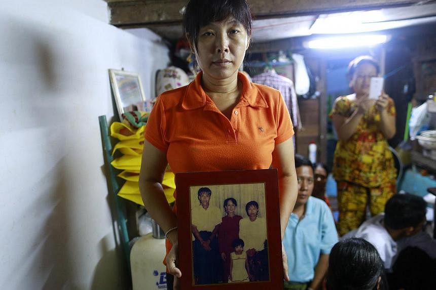 Than Dar, the wife of slain journalist Par Gyi, holds a family photograph showing herself, her husband and daughter posing with Aung San Suu Kyi at their home, in Yangon Oct 28, 2014. &nbsp;A group of activist organisations in Myanmar demanded the se