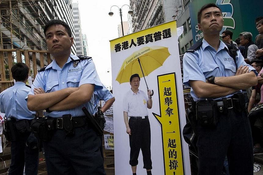 Police stand beside a cutout made by pro-democracy protesters featuring a photo of Chinese President Xi Jinping holding a yellow umbrella, at Mongkok shopping district in Hong Kong on Oct 26, 2014.&nbsp;Waxworks of Chinese Communist Party luminaries,
