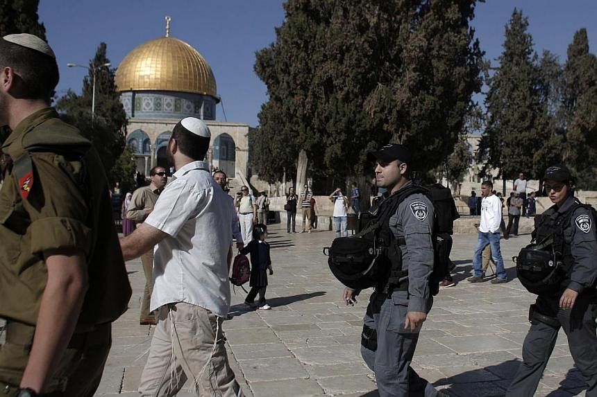 A Jewish visitor protected by Israeli security forces near Jerusalem's Dome of the Rock mosque in the Al-Aqsa mosque compound on Oct 27, 2014. -- PHOTO: AFP