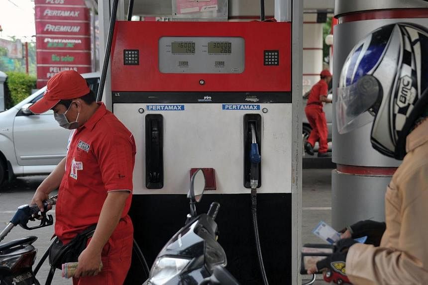 A worker (left) filling a motorcycle with non-subsidised gasoline at a fuel station in Jakarta on Aug 29, 2014.&nbsp;Indonesia's new government will make changes to its costly gasoline and diesel subsidies before the end of the year, the country's ch