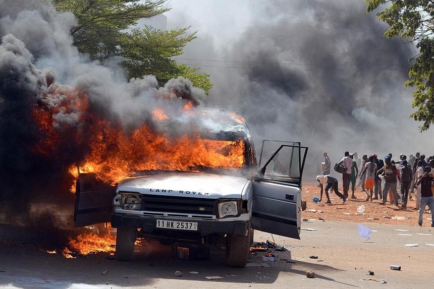 Cars and documents burn outside the parliament in Ouagadougou on Oct 30, 2014.&nbsp;-- PHOTO: AFP