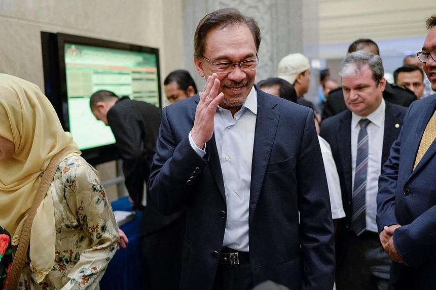 Malaysian Opposition leader Anwar Ibrahim (centre) waves to photographers as he arrives at the federal court in Putrajaya on Oct 30, 2014. -- PHOTO: AFP