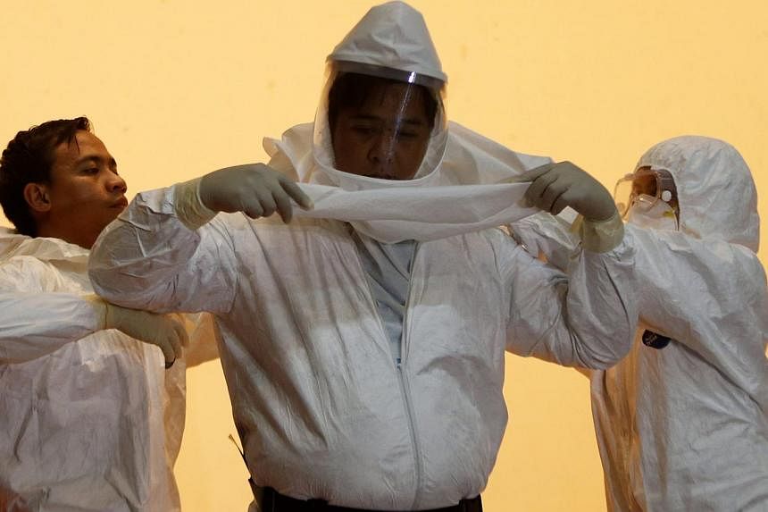 Philippine health workers assist a colleague to don a hazmat suit during a media tour displaying the government's measures in preparing against Ebola at the Research Institute for Tropical Medicine Hospital, at Alabang, Muntinlupa on Oct 21, 2014. --