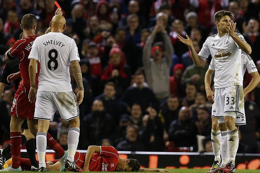 Swansea City's Federico Fernandez (right) reacts after being shown a red card during their English League Cup soccer match against Liverpool at Anfield in Liverpool, northern England, on Oct 28, 2014. -- PHOTO: REUTERS