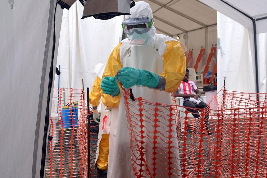 A health worker wearing Personal Protective Equipment (PPE) sets up a fence at the Ebola treatment center in Monrovia, Liberia, on Oct 27, 2014. -- PHOTO: AFP