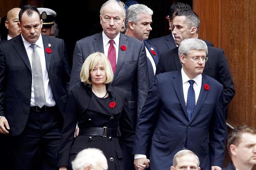 Canadian Prime Minister Stephen Harper and his wife Laureen Harper, with their security detail, after the funeral service for Corporal Nathan Cirillo in Hamilton, Ontario on Oct 28, 2014. Cirillo was shot dead on Oct 22 by a gunman who later charged 