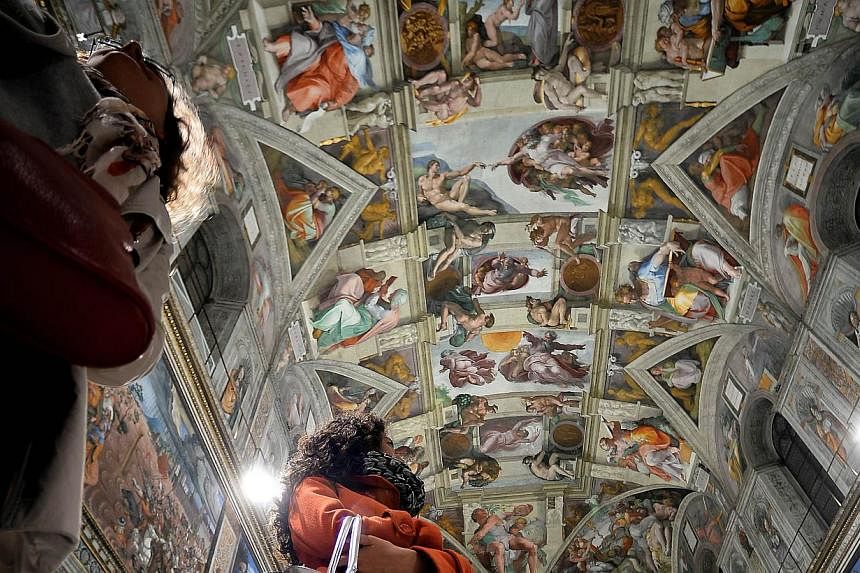 Journalists stare at the Sisitne Chapel with its new lighting during a press visit at the Vatican on Oct 29, 2014. -- PHOTO: AFP